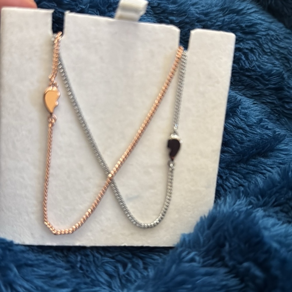Two pieces of heart necklace. Rose gold color and silver color heart halves.